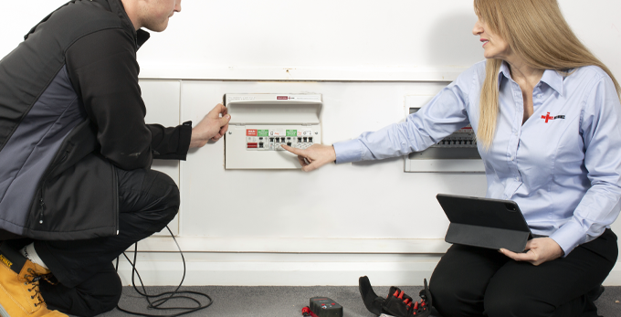 An NICEIC expert providing advise to an approved contractor, whilst on site working on an electric board at a customer's household.