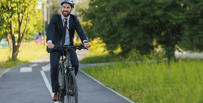 Young male in an elegant suit riding a bicycle in a bike lane on a sunny day.