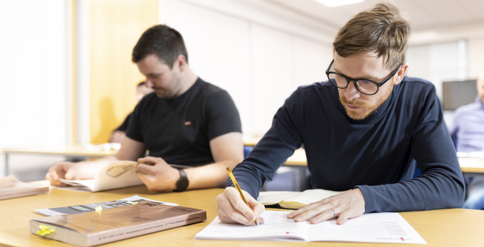 A classroom of contractors writing down notes whilst undertaking a training course delivered by a NICEIC approved specialist.