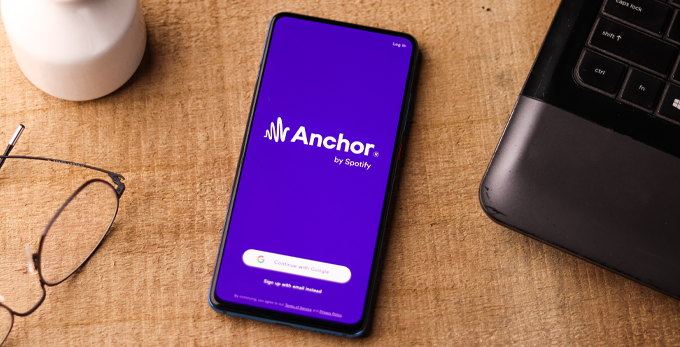 A mobile phone on a desk, with the Anchor Spotify mobile app open.