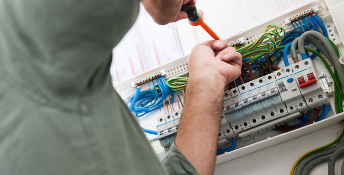 Using a screw driver to reconnect wiring in an electrical board.