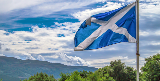 

Scotland flag waving in the wind on a cloudy day at Loch Ness Highlands in Scotland