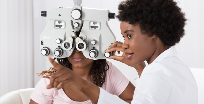 optometrist conducting eye sight test on patient.