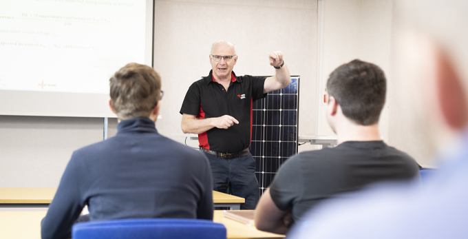 NICEIC approved contractor leading a training course on solar energy, to a class room of tradesmen.