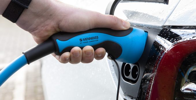 Close up of a EV electrical vehicle being charging with a blue handle mennekes power charger.