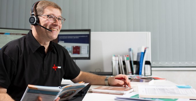 NICEIC Technical Advisor on a call holding a wiring regulations book