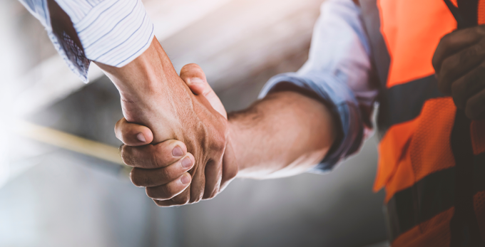 construction worker wearing a hi-viz jacket shaking hands with man in shirt