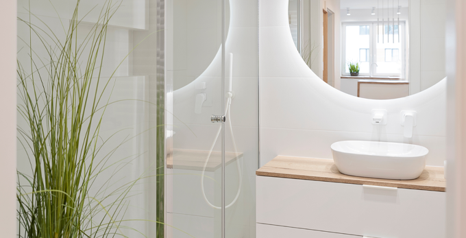 A modern white bathroom, with a circle LED mirror above the sink.