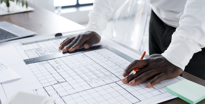 A contractor reviewing architectural blueprints for solar energy installation at the table at the office.