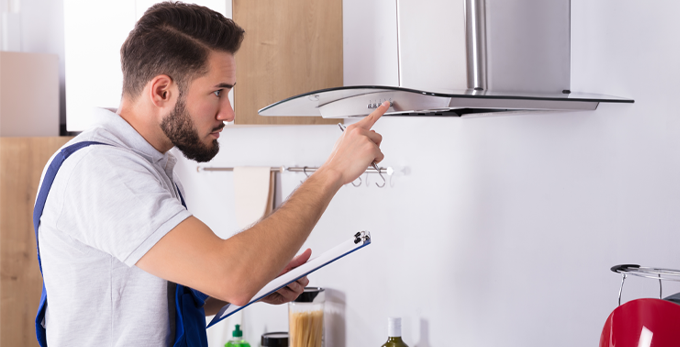 Male electrician with clipboard repairing kitchen extractor filter