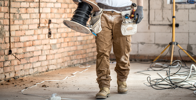 A contractor holding extension cable on construction site working on second fix of socket wiring.